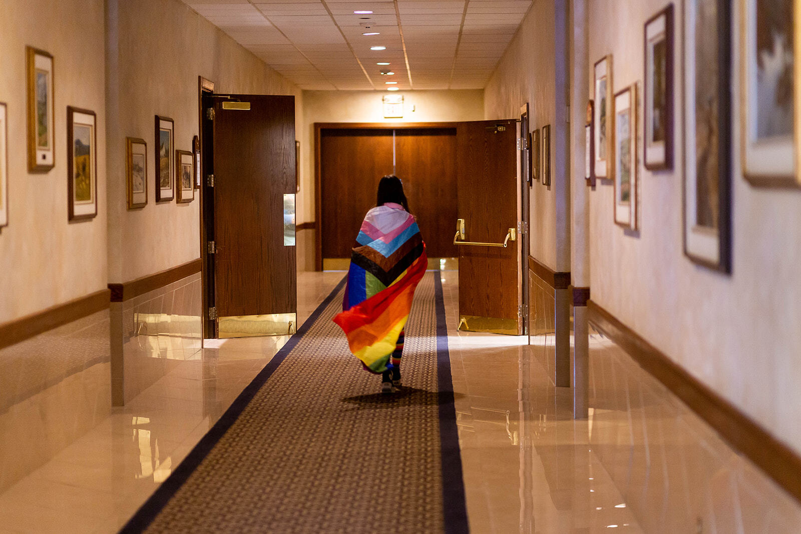 GSA walking down hallway wearing flag